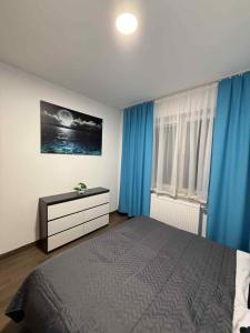 a bedroom with a bed with blue curtains and a dresser at Apartament Zefir in Busko-Zdrój