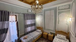 a bedroom with two beds and a chandelier at Rahmat guesthouse in Bukhara