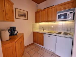 eine Küche mit Holzschränken und einer weißen Mikrowelle in der Unterkunft Spacieux appartement 4 pièces, 8 pers., proche pistes à Vallandry - FR-1-411-849 in Landry