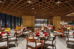 ein Restaurant mit Tischen und Stühlen und Fenstern in der Unterkunft Khách Sạn Apec Mandala Whyndham Tuy Hoa -Phú Yên in Phước Hậu (1)