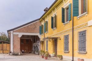 a yellow building with green shutters on it at Ca' Biscòtt in Borgoforte