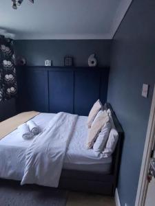 a blue bedroom with a bed with white sheets and pillows at Lancing in Lancing