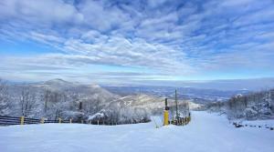 a snow covered hill with a fence and mountains at Red Fox Den - Luxurious home 10 guests 5 beds in Massanutten in McGaheysville