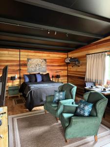 ein Schlafzimmer mit einem Bett und zwei grünen Stühlen in der Unterkunft Chalés no Alto do Capivari - Lar da Serra in Campos do Jordão
