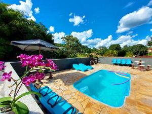 a patio with a swimming pool and purple flowers at Conexão natureza in Socorro