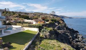 an exterior view of a house with a garden and the water at Il Giardino sul mare in Acireale
