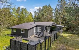 ein kleines Haus im Wald mit einer Terrasse in der Unterkunft 3 Bedroom Amazing Home In Rømø in Kongsmark