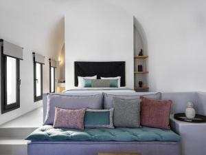 a bedroom with a bed and a couch with pillows at Notia Suite, Jacuzzi, Imerovigli in Imerovigli +17 photos