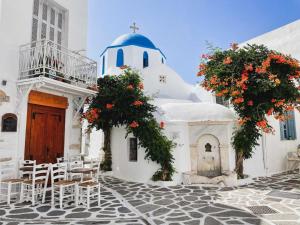 a white building with a chapel and tables and chairs at Notia Suite, Jacuzzi, Imerovigli in Imerovigli