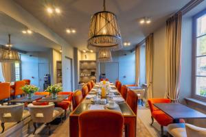 a long dining room with tables and orange chairs at Hotel Ligaro - Jarnac in Jarnac