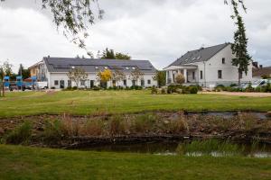 a house with a pond in front of it at Folwark Matecznik - Spichlerz in Sedzinko