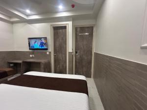 a bedroom with a bed and a tv on the wall at Hotel Shree Guru Plaza 3 Minute Walking Distance From New Delhi Railway Station in New Delhi