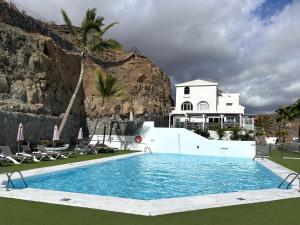 a swimming pool in front of a villa at OceanEye Apartment with heated pool in Mogán