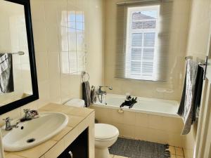 a bathroom with a sink and a toilet and a tub at Little Oasis - Palm Room in Port Elizabeth