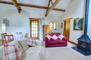 LlanegrynにあるY Bwthynのリビングルーム(赤いソファ、薪ストーブ付)