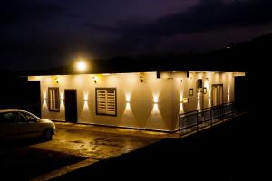 a white building with a car parked in a parking lot at night at Sravan Villa in Vagamon