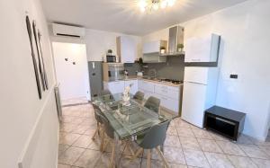 une cuisine avec une table en verre et des chaises. dans l'établissement Fontana Comfort Apartment, à Castelnuovo del Garda