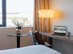 ボルドーにあるPullman Bordeaux Lacの机とテーブルの上にノートパソコンがあるホテルの部屋 +183枚の写真