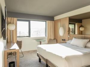 ボルドーにあるPullman Bordeaux Lacの大きな白いベッドと窓のある寝室