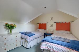 zwei Einzelbetten in einem Schlafzimmer mit roten Akzenten in der Unterkunft Stable Mews Cottage in Royal Tunbridge Wells