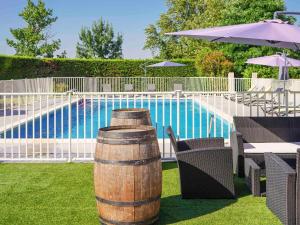 a barrel sitting in the grass next to a pool at ibis Beziers Est Mediterranee A9/A75 in Béziers
