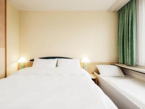 a bedroom with two beds and green curtains at ibis Paderborn City in Paderborn