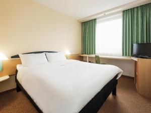 a hotel room with a large bed and a television at ibis Paderborn City in Paderborn