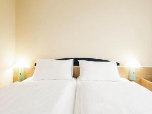 two beds in a room with white sheets and lamps at ibis Paderborn City in Paderborn +39 photos