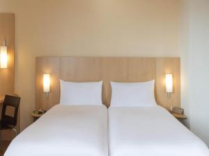 two beds in a hotel room with two white pillows at ibis Metz Centre Gare in Metz