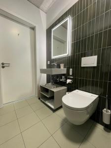 a bathroom with a toilet and a sink and a mirror at Aparthotel Il Momento Bern Expo - Self Check-In Hotel in Bern +26 photos