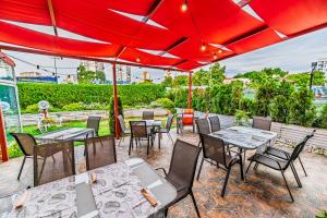 um pátio com mesas e cadeiras sob um guarda-sol vermelho em Art Hotel Simona em Sófia