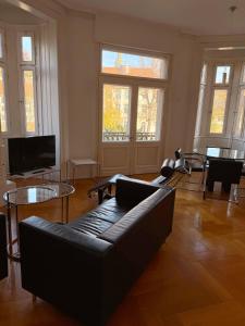 a living room with a couch and tables and windows at MAVO Hospitality Esslingen Bahnhofstraße in Esslingen +15 photos