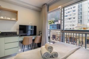 a bedroom with a balcony with a bed and a television at 360 Ascent Paulista in Sao Paulo