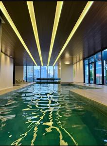 an indoor pool with green water in a building at Studio perto Shopping Estação com Piscina interna aquecida, Academia e Terraço Lindo pôr do Sol in Curitiba