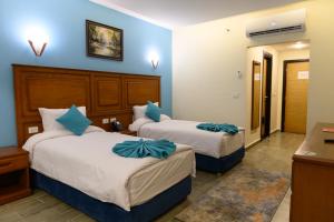 Dos camas en una habitación de hotel con paredes azules. en Aracan Hotac Ras El Bar, en Ras El Bar