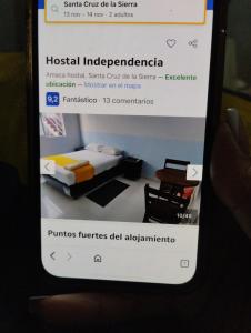 une main tenant un téléphone avec la photo d'un lit dans l'établissement Hostal independencia, à Santa Cruz de la Sierra