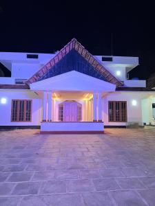 a large white house with a courtyard at night at Haveninn in Athirappilly