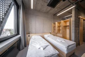two beds in a room with a large window at Hotel Aréna in Jihlava