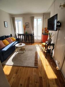 a living room with a blue couch and a table at Lumineux & cosy proche Paris & La Défense, commerces & transports, PARKING in Suresnes