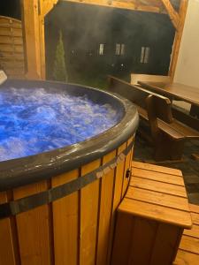 a large hot tub with a bench next to a table at Dworek pod Krzyżtoporem Ujazd Agroturystyka- pokoje do wynajęcia in Iwaniska
