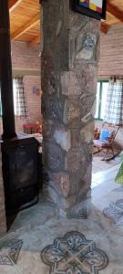 Una chimenea de piedra en una sala de estar con televisión. en CASA QUINTA en ESTANCIA VIEJA, en Villa Carlos Paz