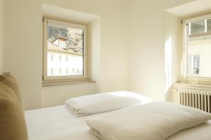 Una habitación blanca con dos camas y una ventana. en HEIMAT - comfy Apartment, en Silandro