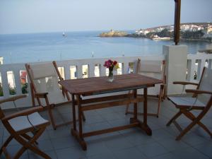 a wooden table with a vase of flowers on a balcony at Vassiliki Studios in Andros