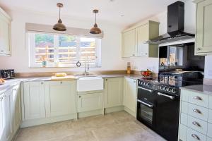 a kitchen with white cabinets and black appliances at Pentwyn Cottage, Bwlch Brecon in Bwlch