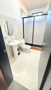 a bathroom with a toilet and a sink and a mirror at Habitación 3 en Villa Mariaclaudia in Macas