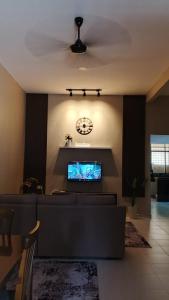 ein Wohnzimmer mit einer Couch und einer Uhr an der Wand in der Unterkunft POOL CaSSa Ardina pantai Batu hitam 4rooms in Kuantan