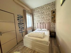a bedroom with a bed and a brick wall at A l'abri des vagues in Cayeux-sur-Mer