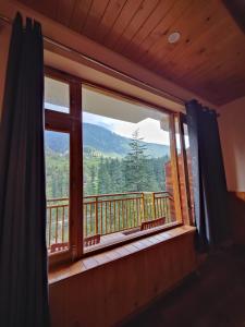 a window with a view of a mountain view at Yellow Stone Cottage and Cafe in Jibhi