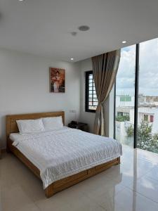 une chambre avec un lit et une grande fenêtre dans l'établissement Ruby Hotel Biển Vũng Tàu, à Vung Tau