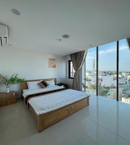 une chambre avec un grand lit et une grande fenêtre dans l'établissement Ruby Hotel Biển Vũng Tàu, à Vung Tau
